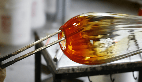 Blown glass piece being shaped with metal tools